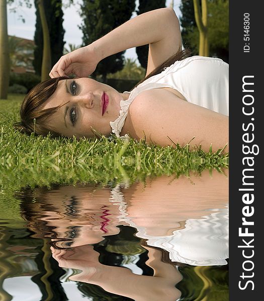 Portrait of a woman lying on the grass with water reflection. Portrait of a woman lying on the grass with water reflection