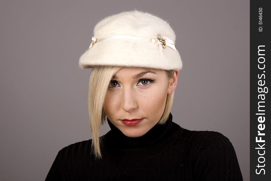 A blonde in black turtleneck and white fur hat and a sad expression. A blonde in black turtleneck and white fur hat and a sad expression