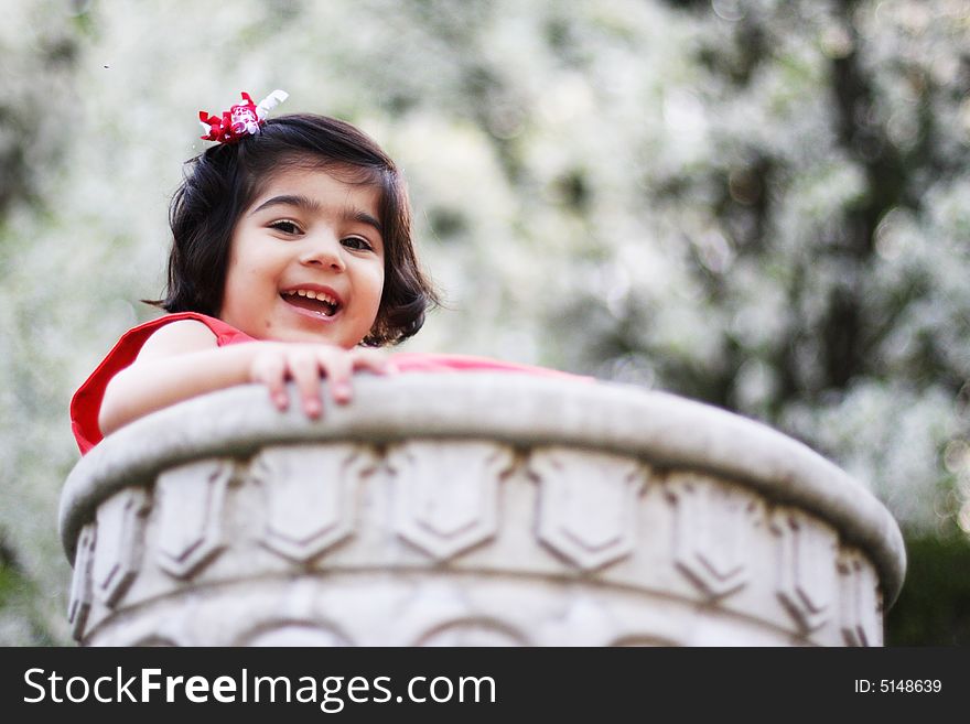 2 year old toddler sitting in a flower pot with a gorgeous white flower bokeh in the back. 2 year old toddler sitting in a flower pot with a gorgeous white flower bokeh in the back
