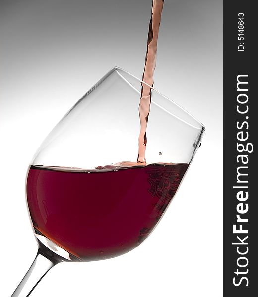 A malbec glass pouring with red wine. A malbec glass pouring with red wine