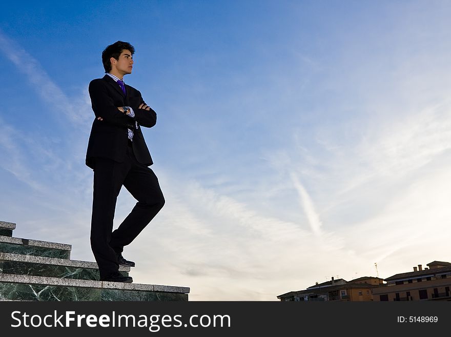 Businessman posing on stairs against blue sky. Businessman posing on stairs against blue sky.