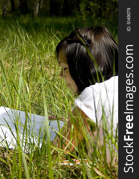 Pretty young girl reading on the grass