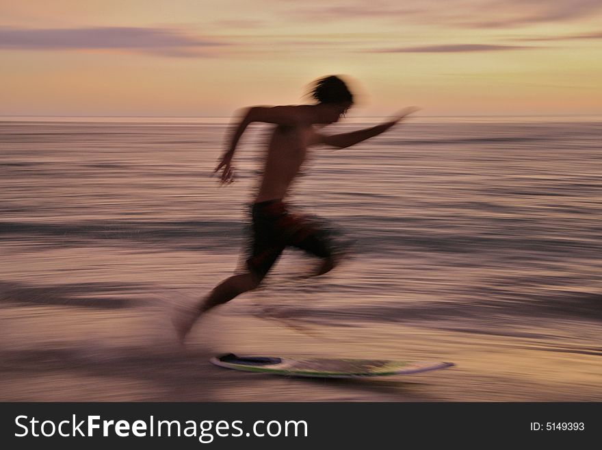 Teenager running and jumping on to boogie board at the beach - motion blur. Teenager running and jumping on to boogie board at the beach - motion blur