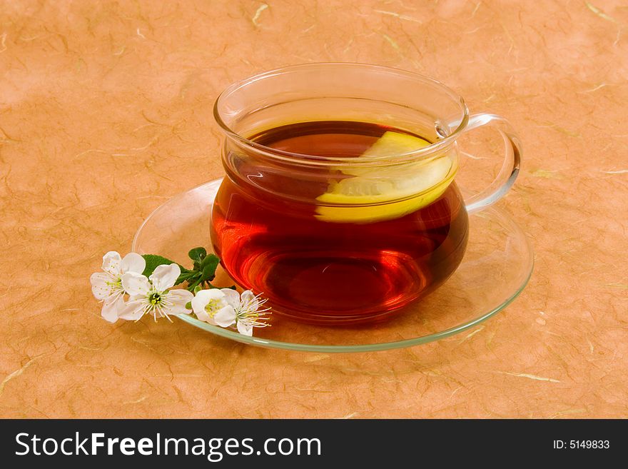 Tea with lemon on glass cup on an orange background.