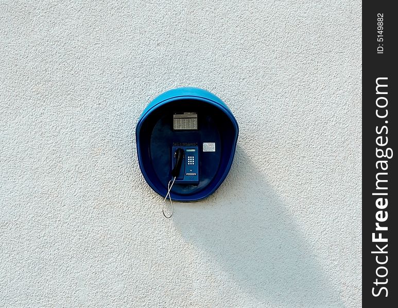 The street paid phone hanging on a wall