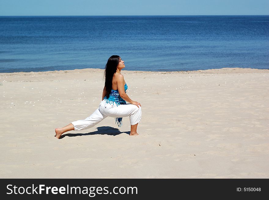 Attractive brunette woman doing exercise on the beach. Attractive brunette woman doing exercise on the beach