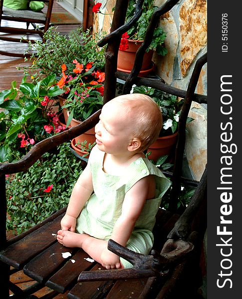Baby boy on willow rocking chair on front porch of family home. Baby boy on willow rocking chair on front porch of family home