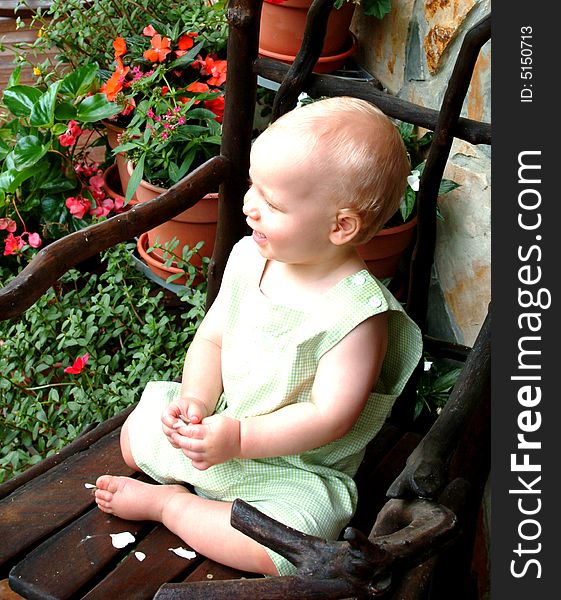 Baby boy on willow rocking chair on front porch of family home. Baby boy on willow rocking chair on front porch of family home