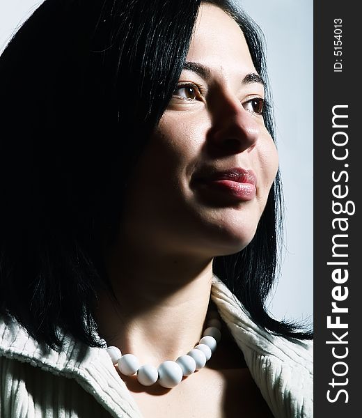 A high-key portrait about a happy young pretty lady with black hair who is smiling and she has a glamorous look. She is wearing a white coat and a white necklace. A high-key portrait about a happy young pretty lady with black hair who is smiling and she has a glamorous look. She is wearing a white coat and a white necklace.