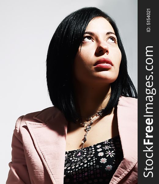 A closeup portrait about an elegant trendy woman with black hair who is looking up and she is dreaming something. She is wearing a nice dress, a stylish necklace and a pink coat. A closeup portrait about an elegant trendy woman with black hair who is looking up and she is dreaming something. She is wearing a nice dress, a stylish necklace and a pink coat.