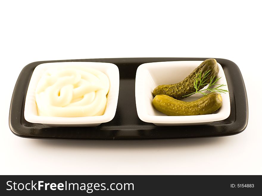 Mayonnaise and pickled gherkin over black plate
