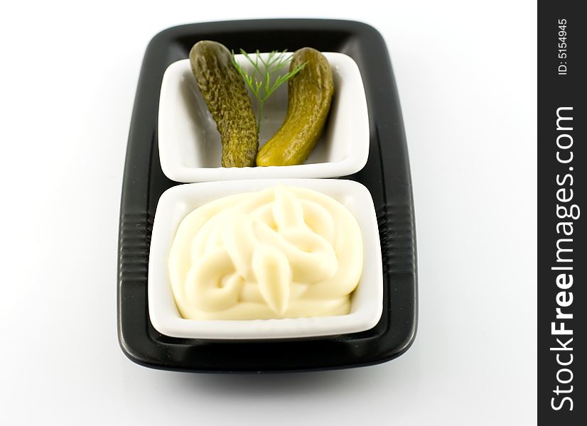 Mayonnaise and pickled gherkin over black plate. Mayonnaise and pickled gherkin over black plate
