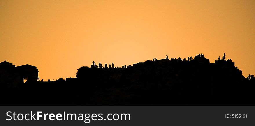 People silhouetted against the sunset along the cliff Santorini