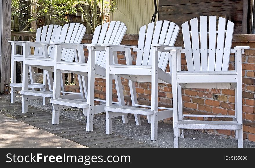 Five high adirondack white wooden chairs at an outside bar. Five high adirondack white wooden chairs at an outside bar