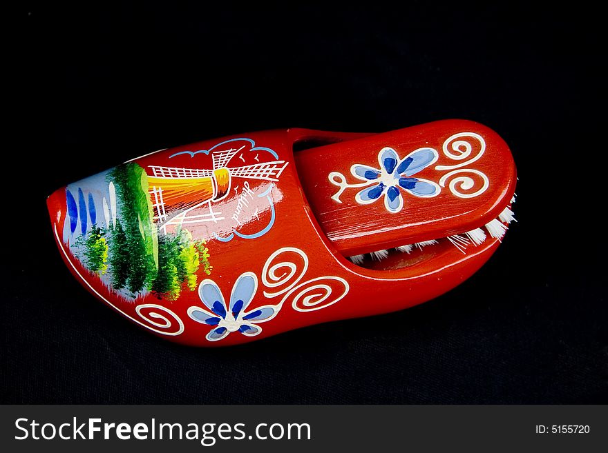 Red shoe brush with natural wild bristles and wooden grip isolated on black background