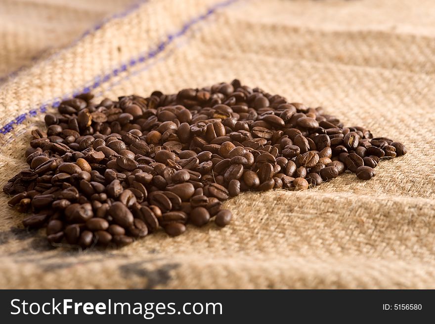 Roasted Coffee beans lying on top of a brown burlap coffee bean transportation bag