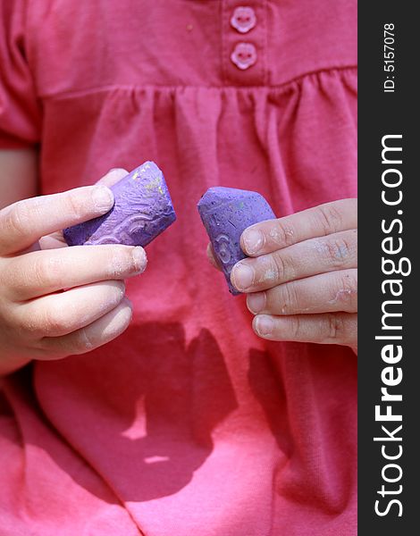 Girl with colorful pink shirt holding purple sidewalk chalk in the summer. Girl with colorful pink shirt holding purple sidewalk chalk in the summer