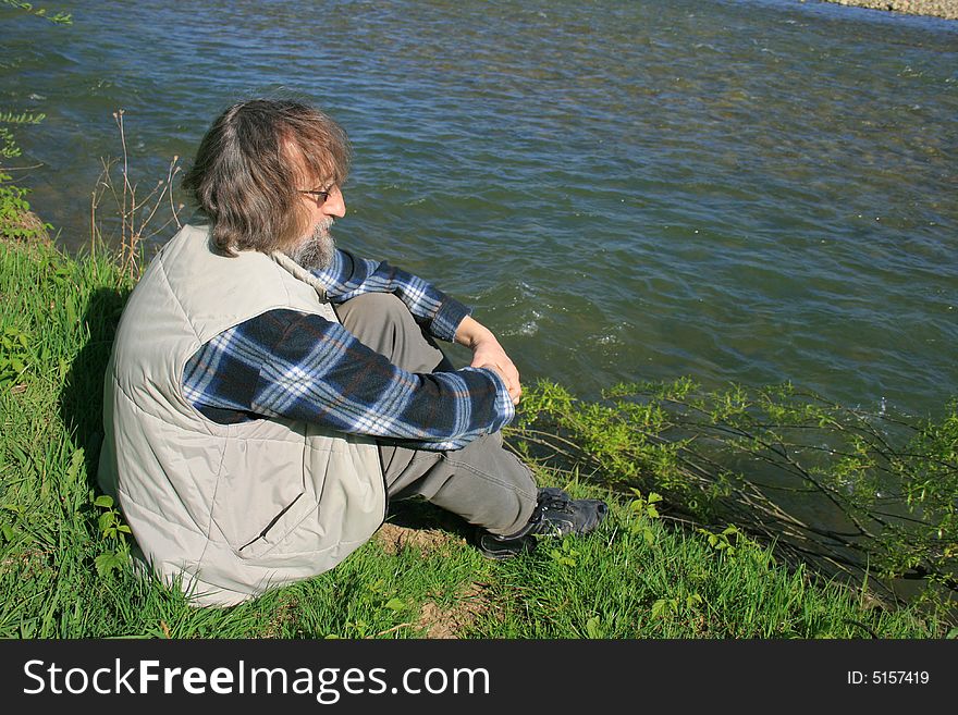 Man sitting by the river and watching water flows. Man sitting by the river and watching water flows