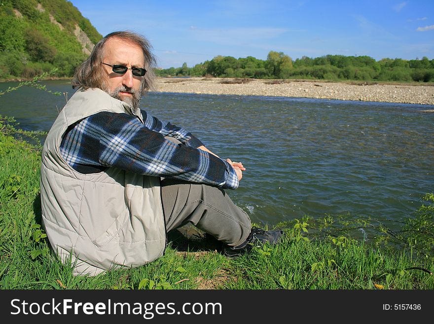 Man relaxing by the river on a spring sunny warm day. Man relaxing by the river on a spring sunny warm day