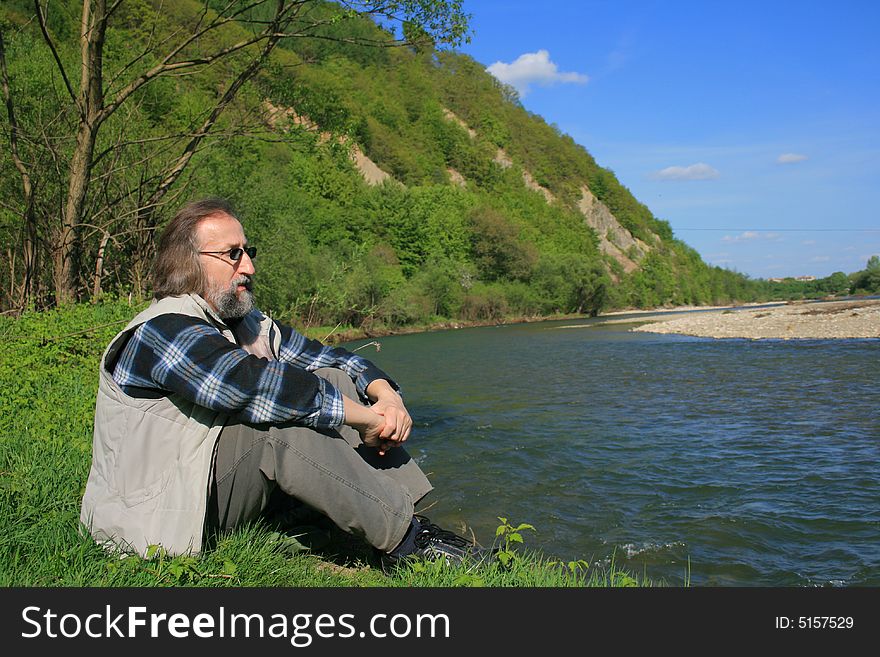 Man relaxing by the river on a spring sunny warm day. Man relaxing by the river on a spring sunny warm day