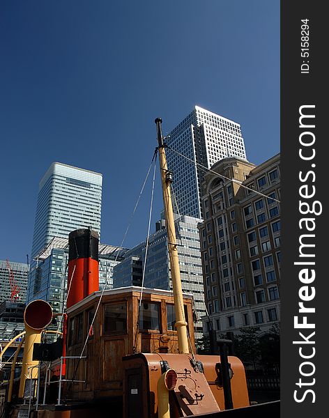 A old wooden boat by the waterside with the office tower skyline of the business and financial district in London. A old wooden boat by the waterside with the office tower skyline of the business and financial district in London.