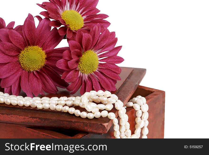 White real pearls with bright pink flowers on aged dark wooden box, isolated on white background. White real pearls with bright pink flowers on aged dark wooden box, isolated on white background