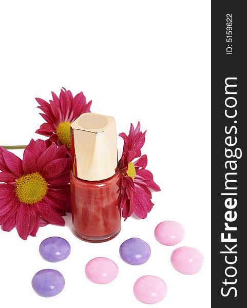 Fashionable dark pink nail polish with flowers and colorful candy isolated on white background. Fashionable dark pink nail polish with flowers and colorful candy isolated on white background