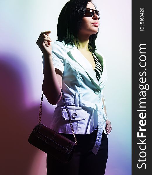 A high-key portrait about a pretty trendy lady with black hair who has a glamorous look. She is lighted colorful and brightly. She is wearing sunglasses, black pants, a white coat and a stylish handbag. A high-key portrait about a pretty trendy lady with black hair who has a glamorous look. She is lighted colorful and brightly. She is wearing sunglasses, black pants, a white coat and a stylish handbag.