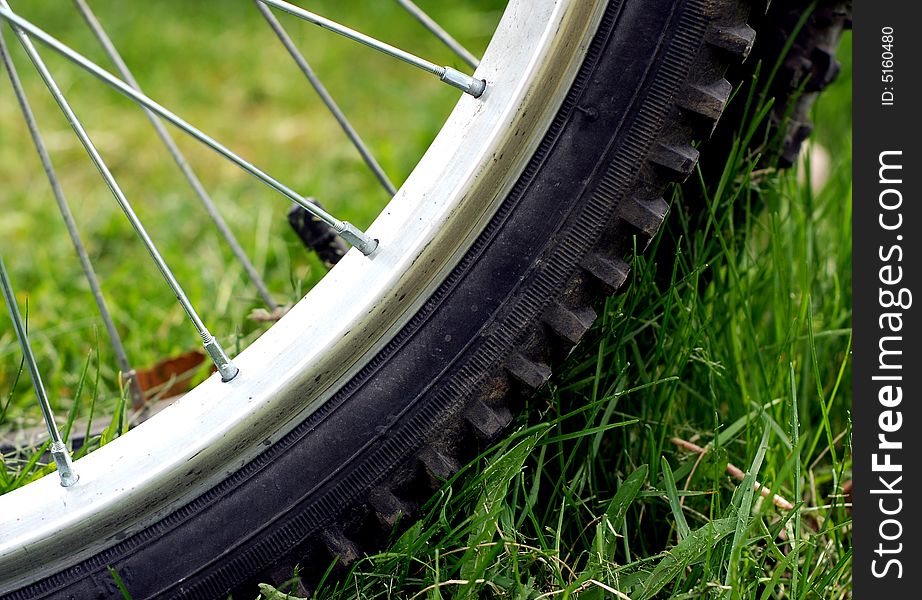 Close up view of a parked bicycle tire on green grass. Close up view of a parked bicycle tire on green grass