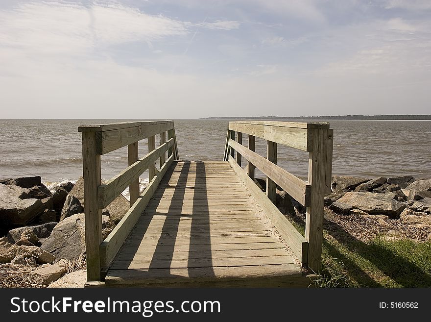 An old weathered walkway across a seawall toward the beach. An old weathered walkway across a seawall toward the beach