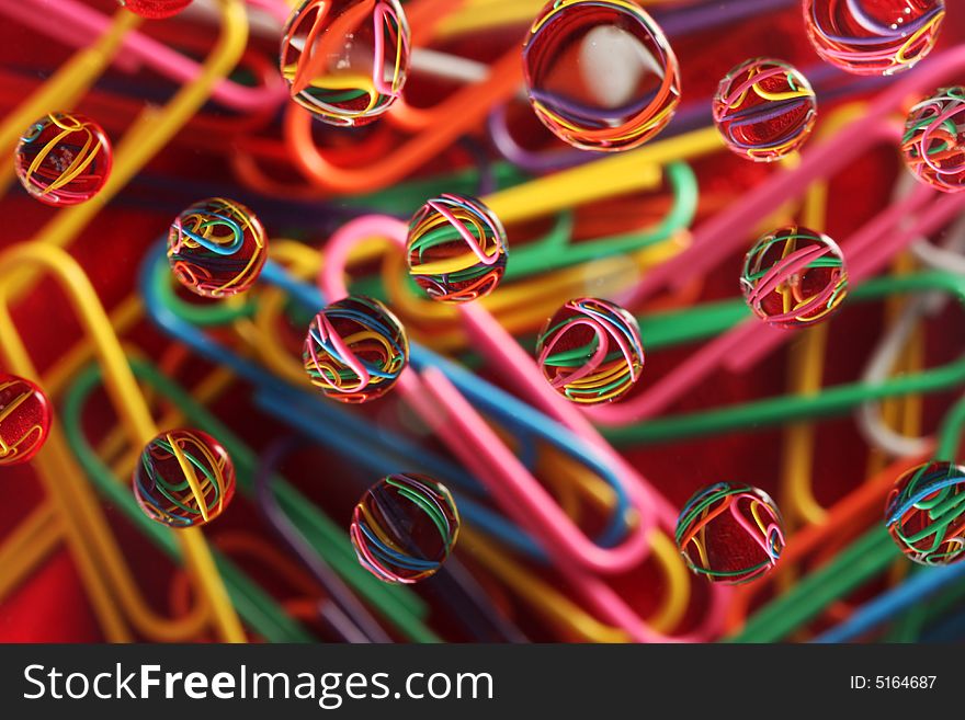 Water drops on top of colorful paperclips, focus on reflection in drops, great for backgrounds and designs. Water drops on top of colorful paperclips, focus on reflection in drops, great for backgrounds and designs