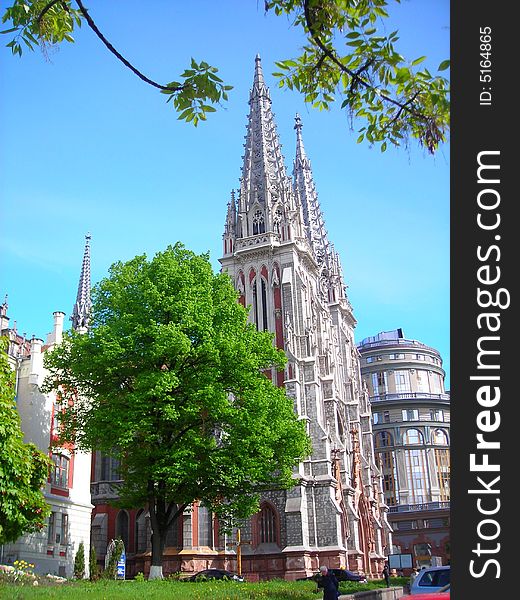 An old catholic cathedral in Europe. Bright sky and green trees