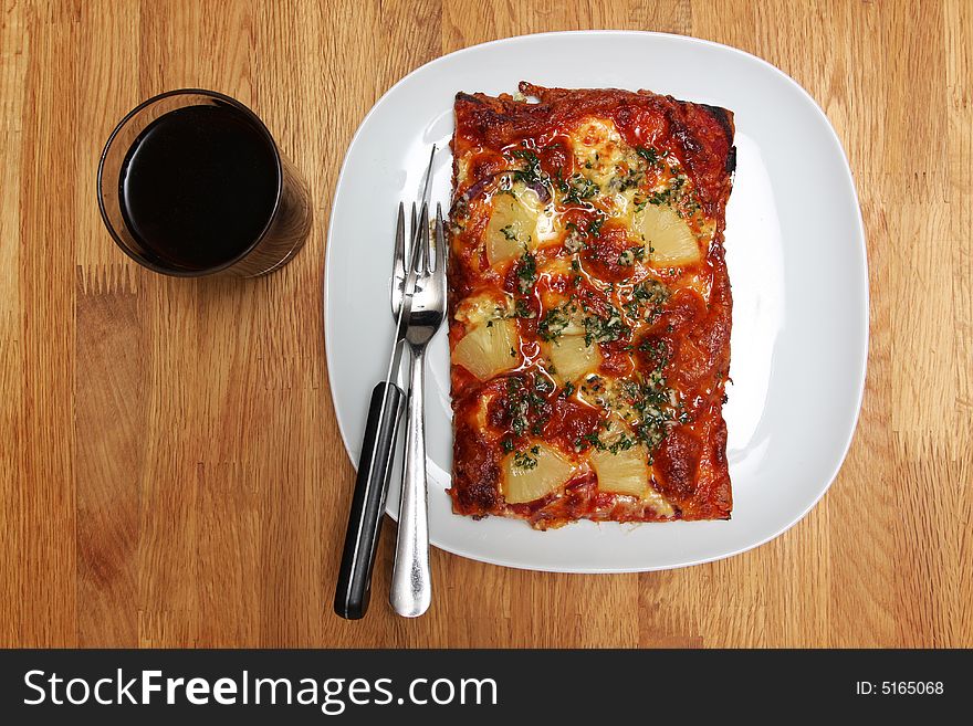 Slice of homemade pizza on a plate with drink and utensils