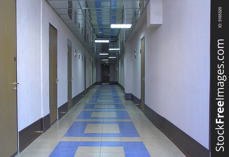 Long hallway with doors, exit on the end and mirror ceiling