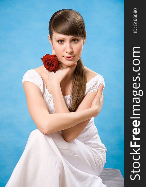Attractive brunette with red rose isolated on blue