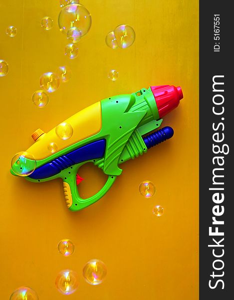 Water-pistol and blow bubbles on yellow background. Water-pistol and blow bubbles on yellow background