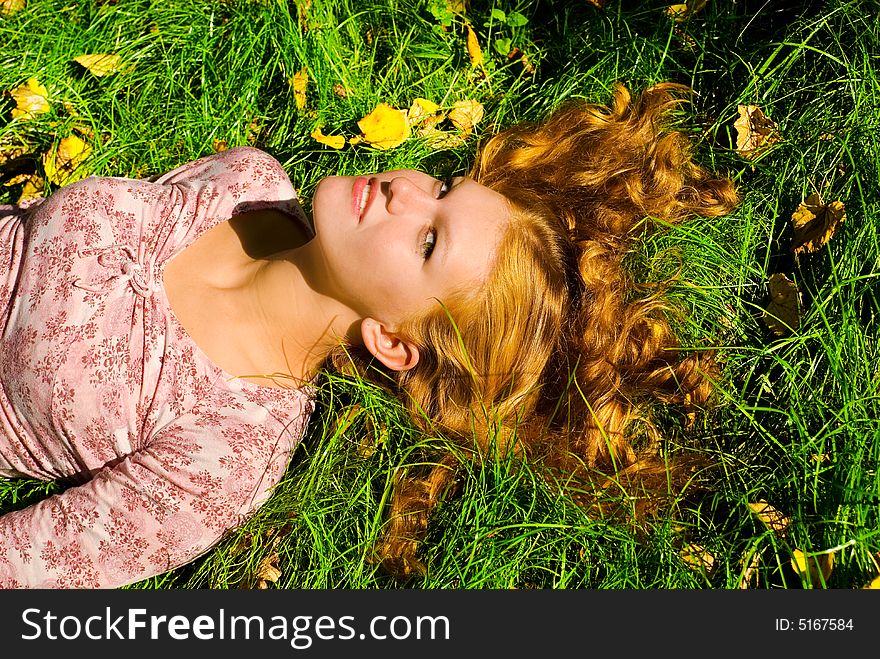 Looking to camera beauty girl with big breast is smiling and relaxing on the grass. Looking to camera beauty girl with big breast is smiling and relaxing on the grass