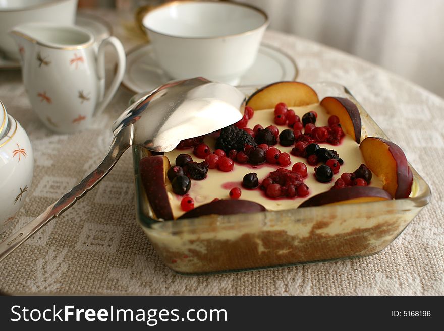 Tea and cake set out onto a linen tablecloth, the cake made from apricots, blueberries, lingonberries, and trifle. Tea and cake set out onto a linen tablecloth, the cake made from apricots, blueberries, lingonberries, and trifle