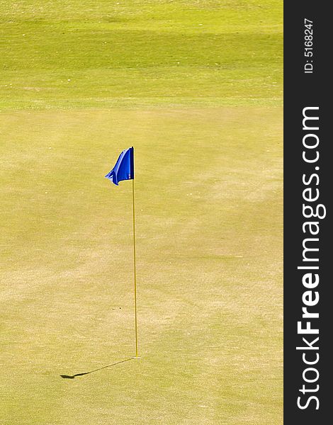 A blue flag marking the hole on the eighteenth green. A blue flag marking the hole on the eighteenth green