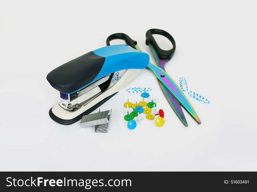 Stapler, scissors, thumbtacks, paper clips on the table. Stapler, scissors, thumbtacks, paper clips on the table