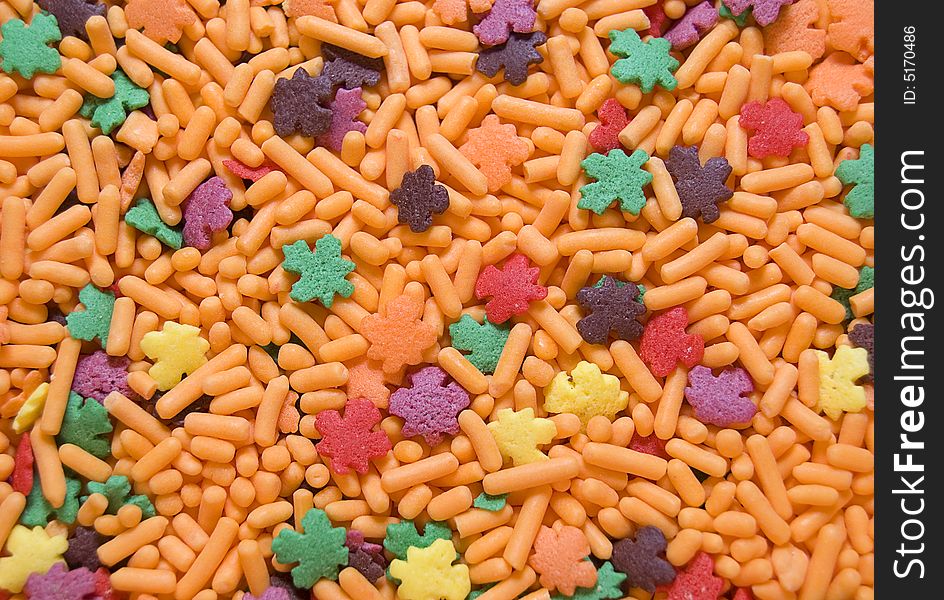 Full frame photograph of orange candy sprinkles with autumn colored leaf shaped candies.