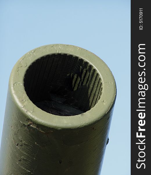 Detail of the World War One canon, isolated on clear blue sky background, spiderweb in the barrel.