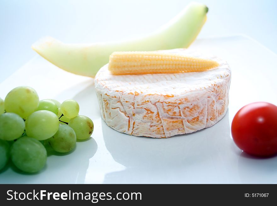 Some cheese on a plate with fruits and vegetables