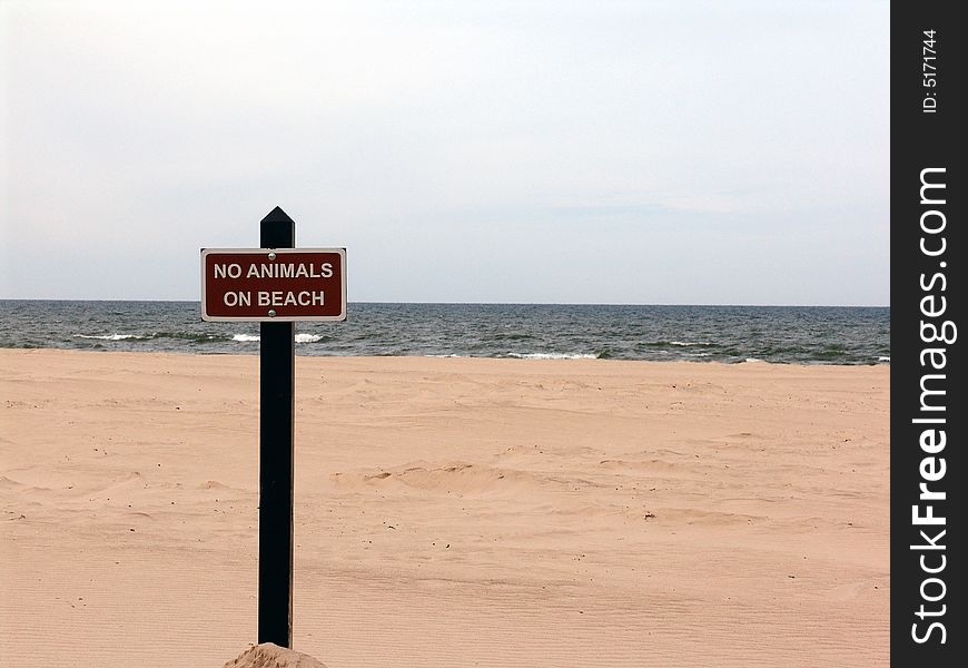 Sign on beach with sand and lake in background. Sign on beach with sand and lake in background