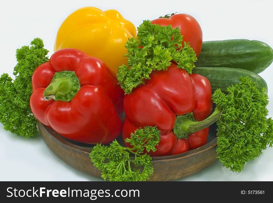 Red and yellow pepper with greens in a basket on a white background. Red and yellow pepper with greens in a basket on a white background.