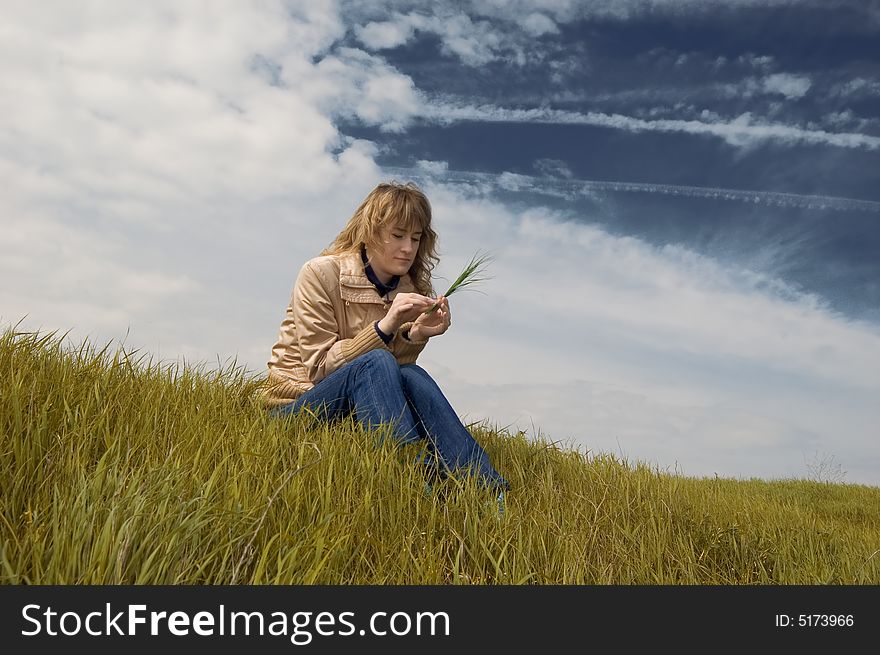 Girl sits on a grass against an autumn landscape. Girl sits on a grass against an autumn landscape
