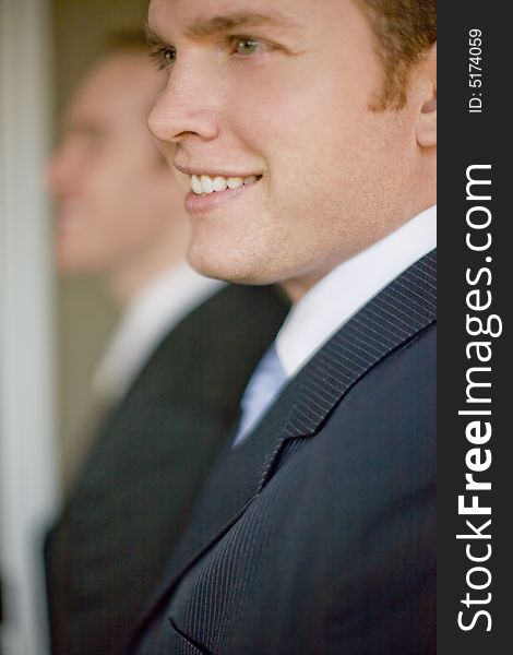 Close up of two businessmen wearing suits smiling in profile view