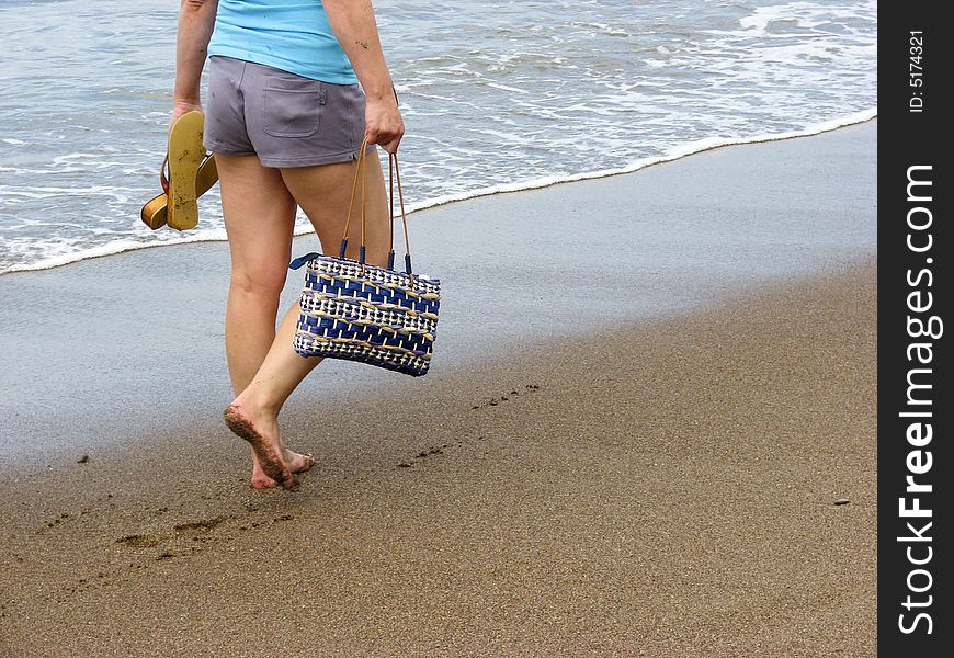 Woman casually strolling on a sandy beach. Woman casually strolling on a sandy beach