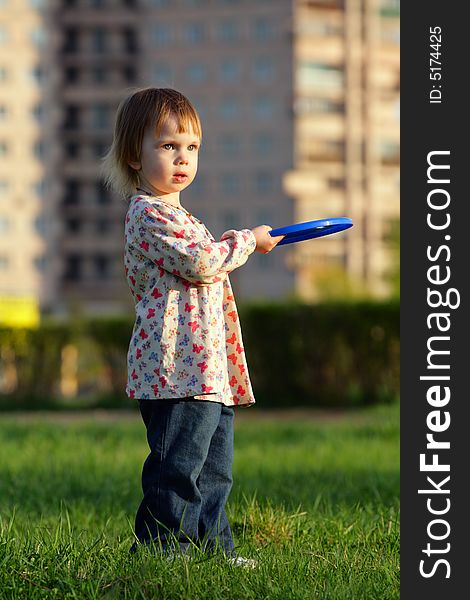 Little beauty girl playing blue frisbee in urban park. Little beauty girl playing blue frisbee in urban park