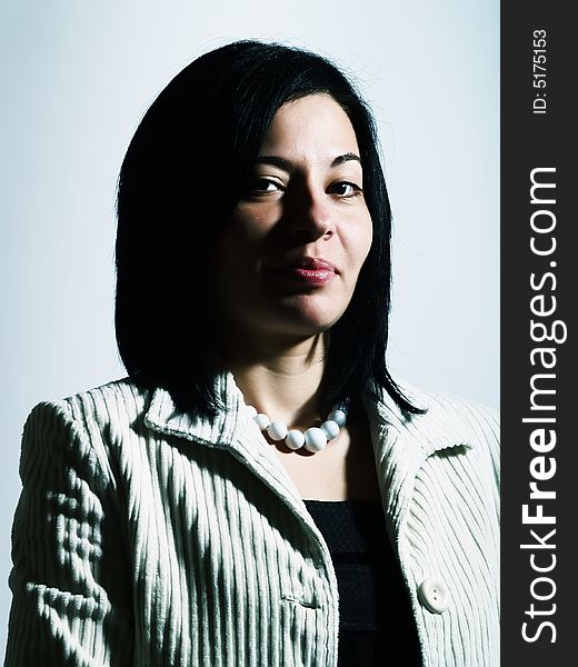 A high-key portrait about an attractive lady with black hair who is looking ahead, she is flirting and she has a charming look. She is wearing a white coat, a black dress, and a white necklace. A high-key portrait about an attractive lady with black hair who is looking ahead, she is flirting and she has a charming look. She is wearing a white coat, a black dress, and a white necklace.